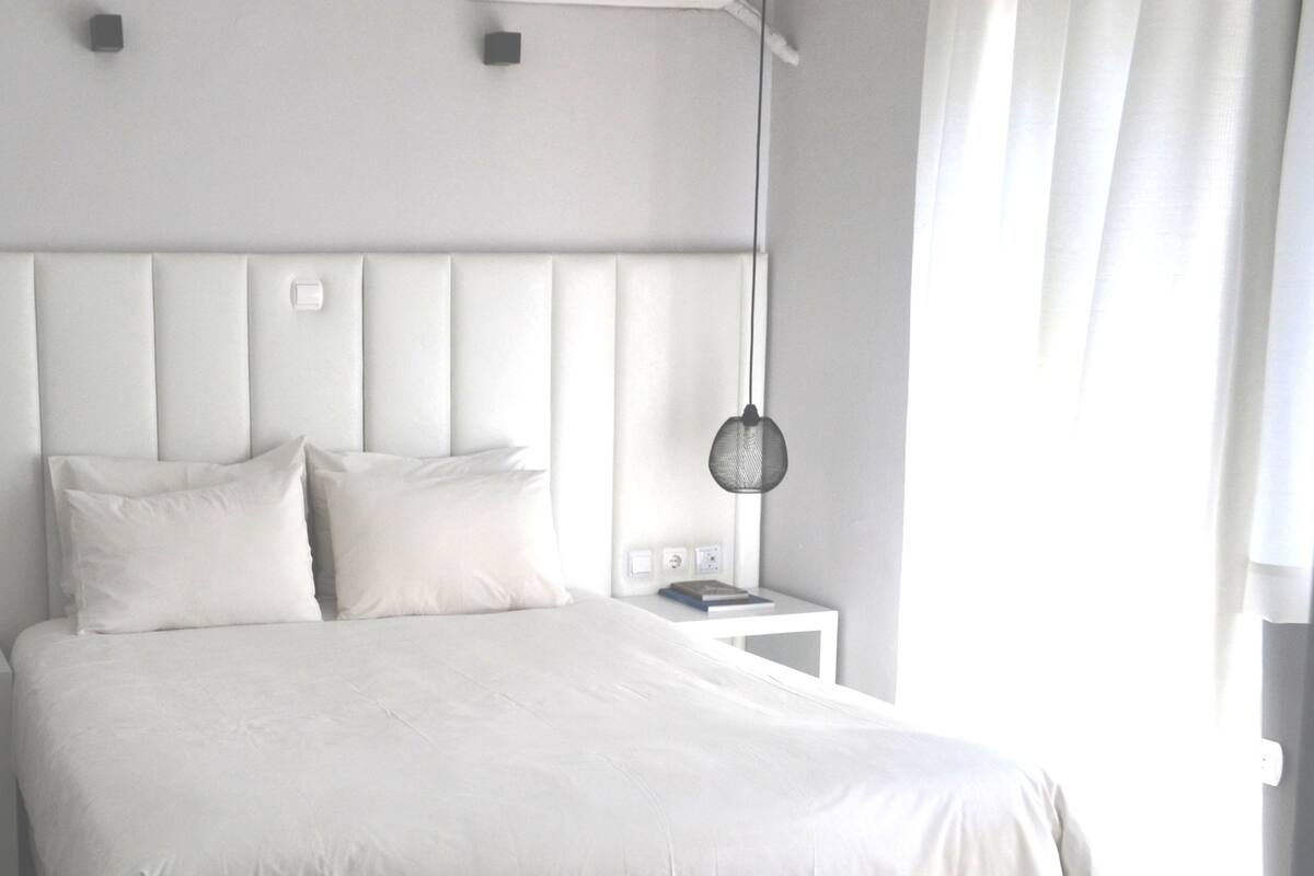 Ein modernes Schlafzimmer mit einem großen Bett, zwei Nachttischen und zwei Hängeleuchten.