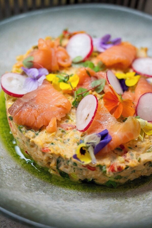 Un plato con salmón, rábanos y flores.