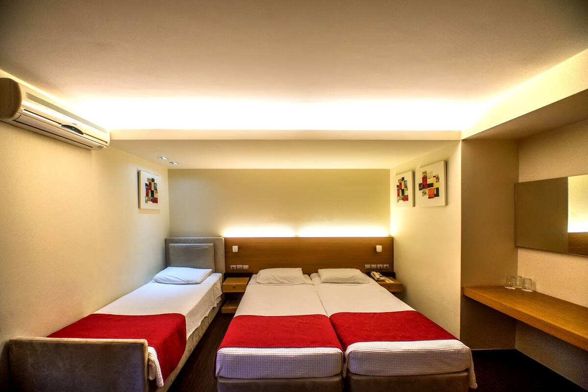Ein Hotelzimmer mit zwei Einzelbetten, einem kleinen Schreibtisch, einem Stuhl und einem Spiegel.