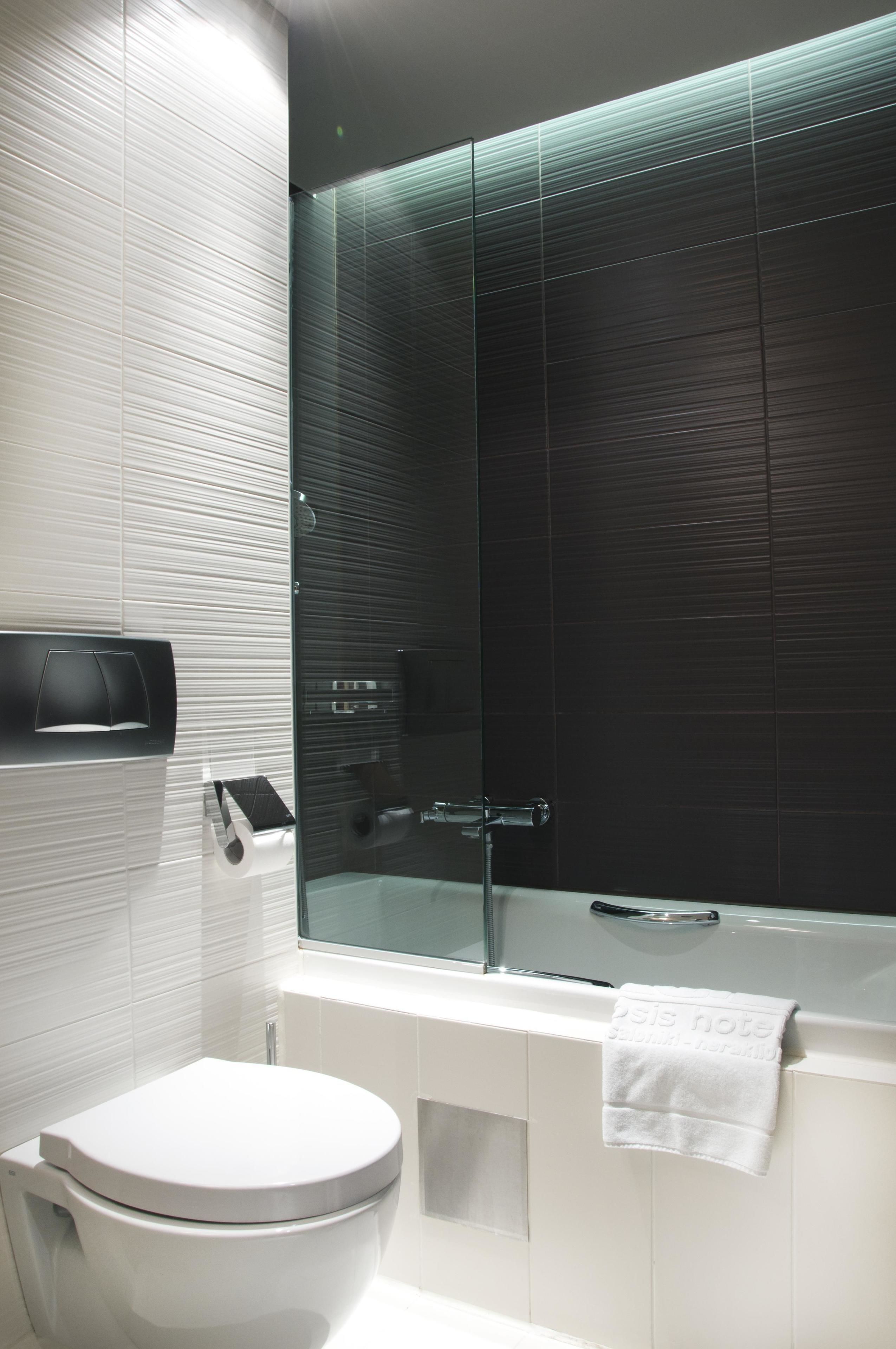 Un baño moderno con inodoro, ducha con mampara de vidrio y bañera.