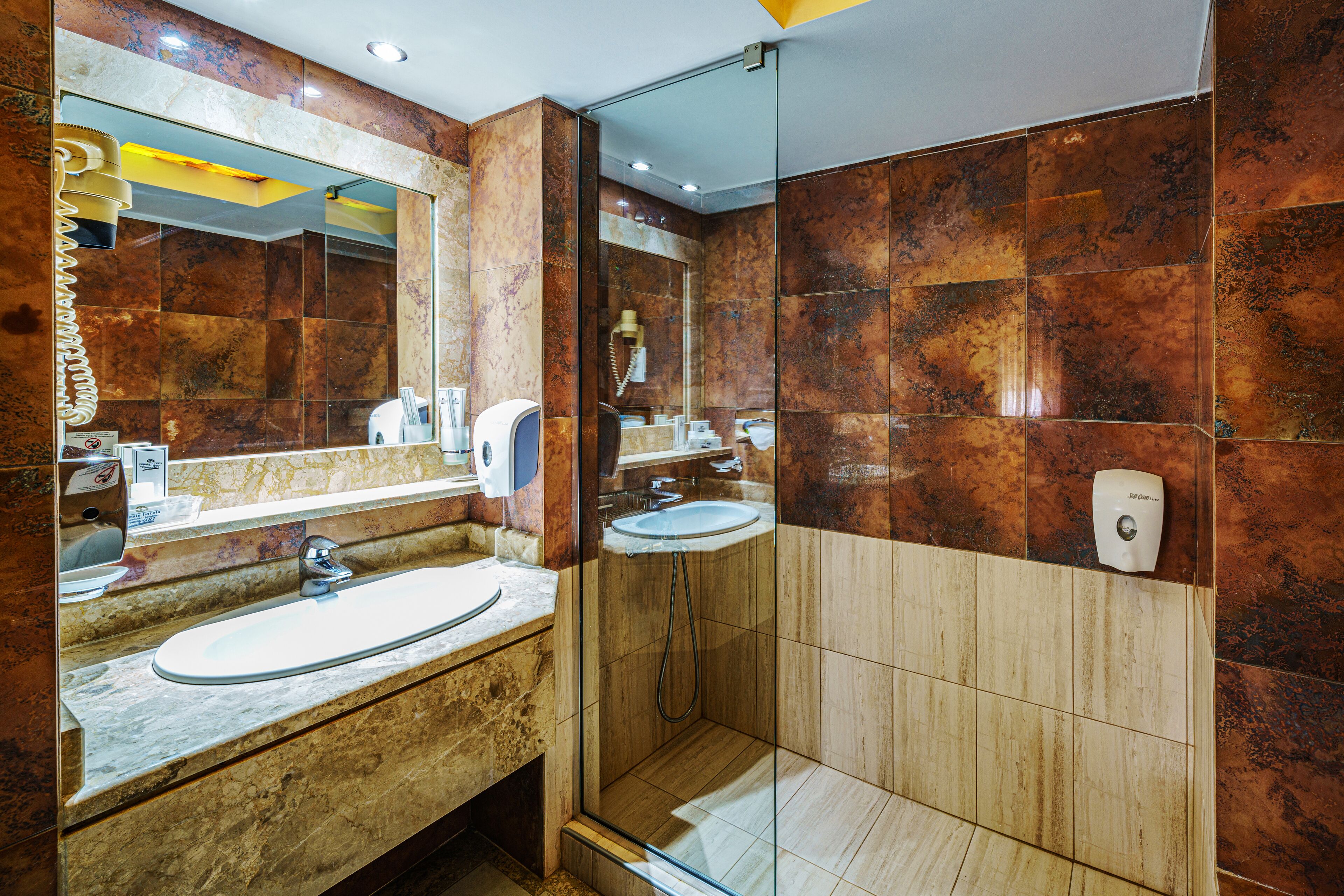 Un baño moderno con tocador de mármol, ducha con cerramiento de vidrio y un espejo grande.