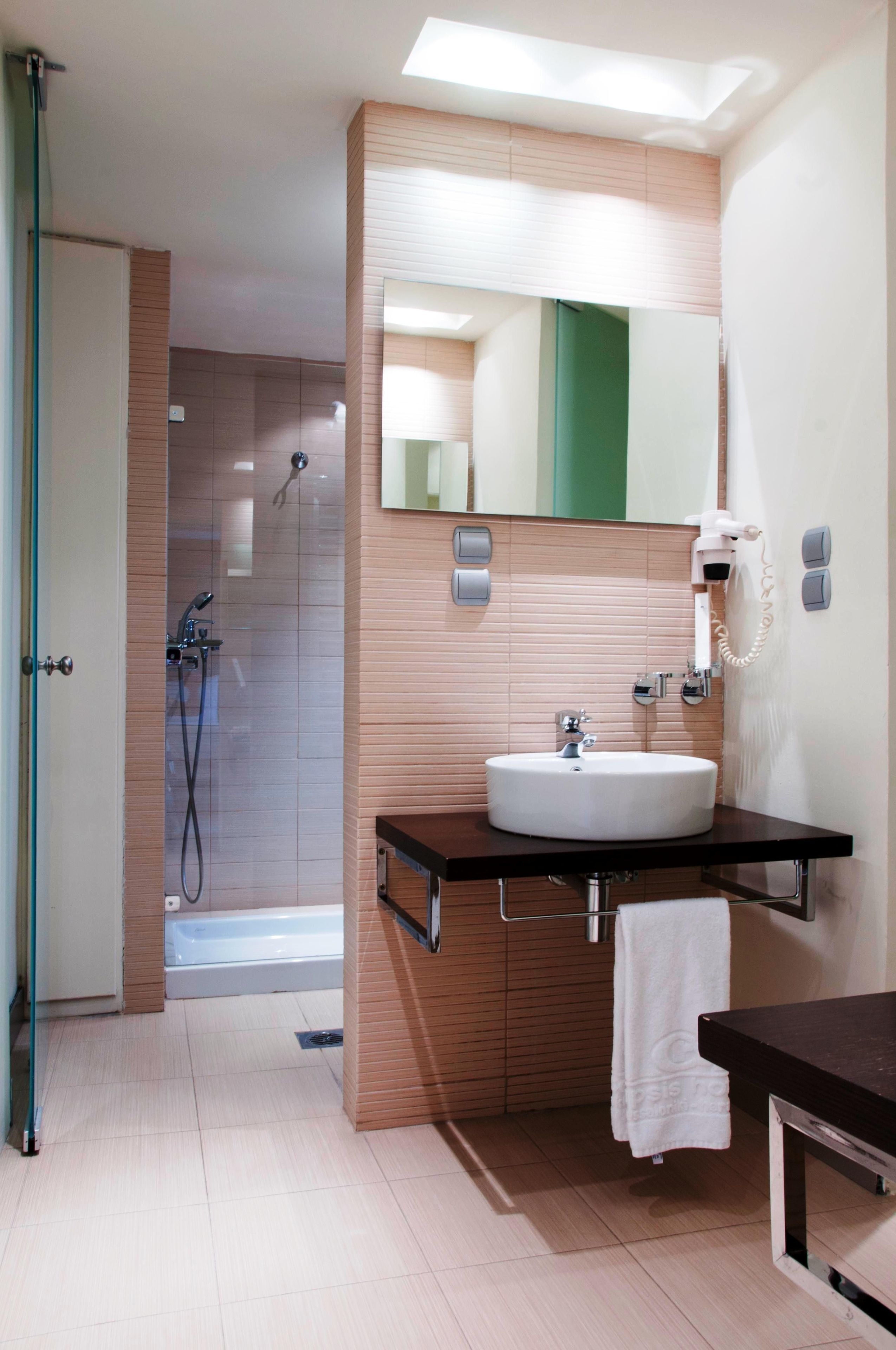 Un bany modern amb una dutxa de vidre, un lavabo blanc i un mirall gran.