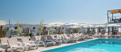 Una piscina al aire libre de temporada, sombrillas