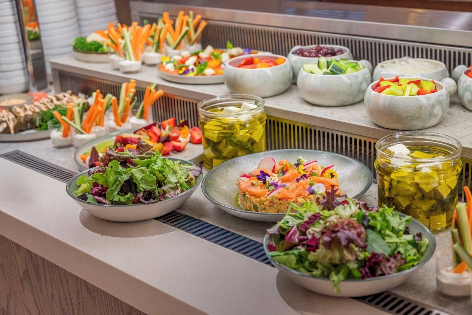 Un buffet proposant une variété de salades, de légumes et de sauces.