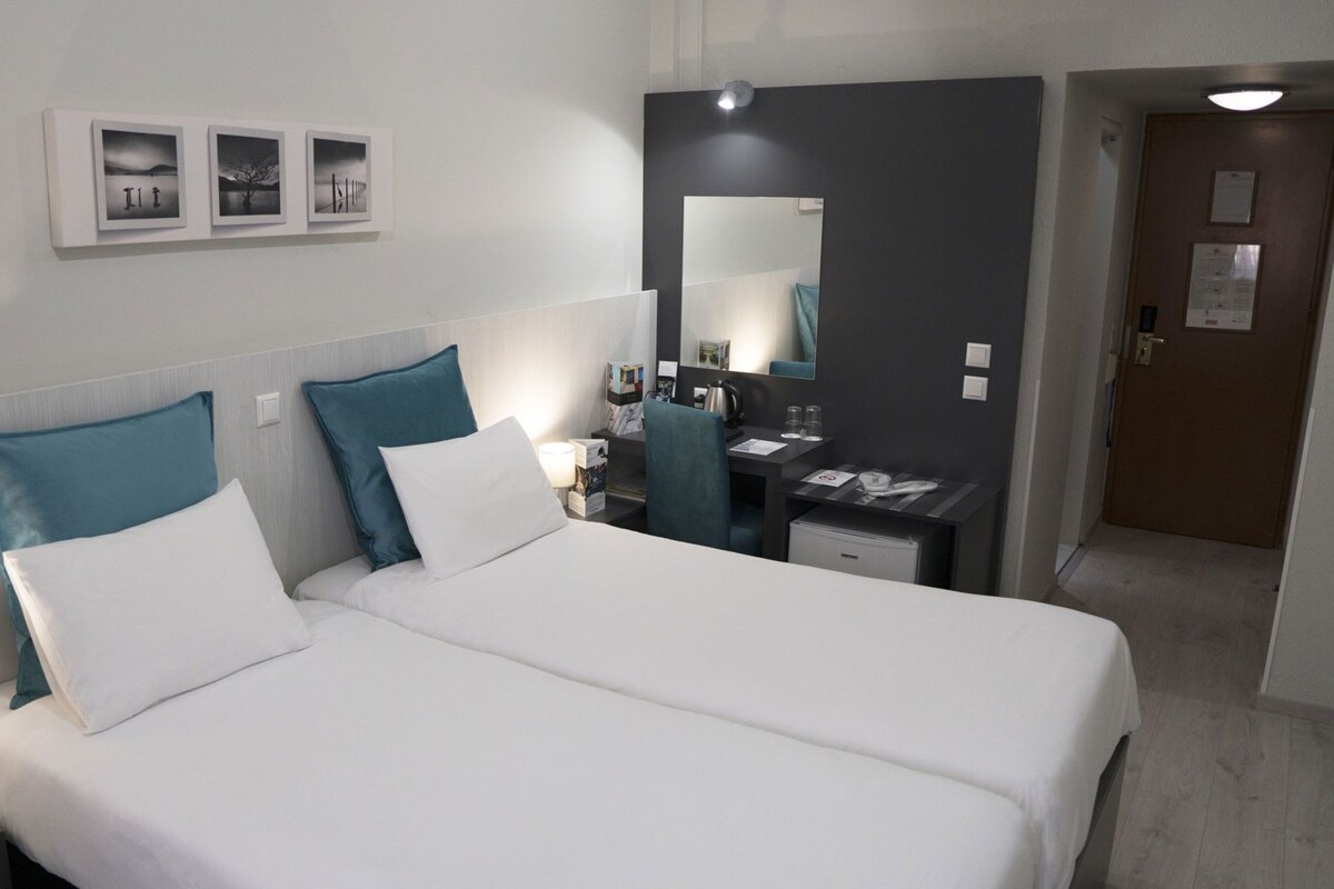 Una habitación de hotel con cama, mesita de noche, lámpara y escritorio con silla.