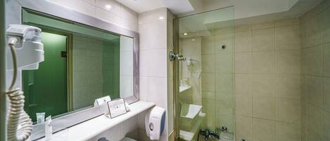 Un baño moderno con un espejo grande, un lavamanos, una ducha con cerramiento de vidrio y un secamanos.