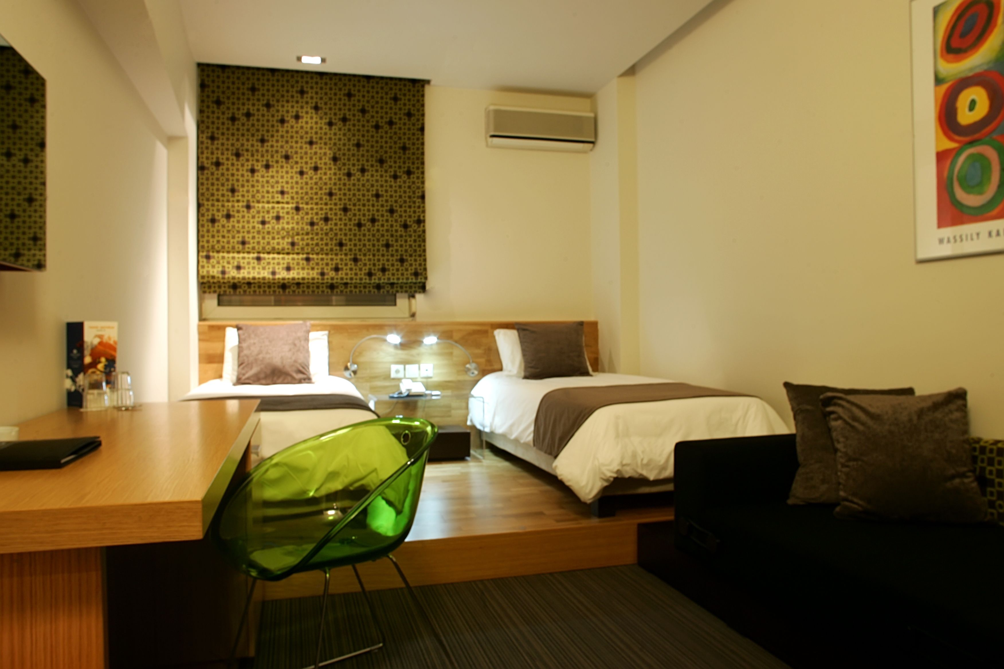 Habitación de hotel con cama, escritorio, sillón, sofá y una cortina decorativa en la pared.
