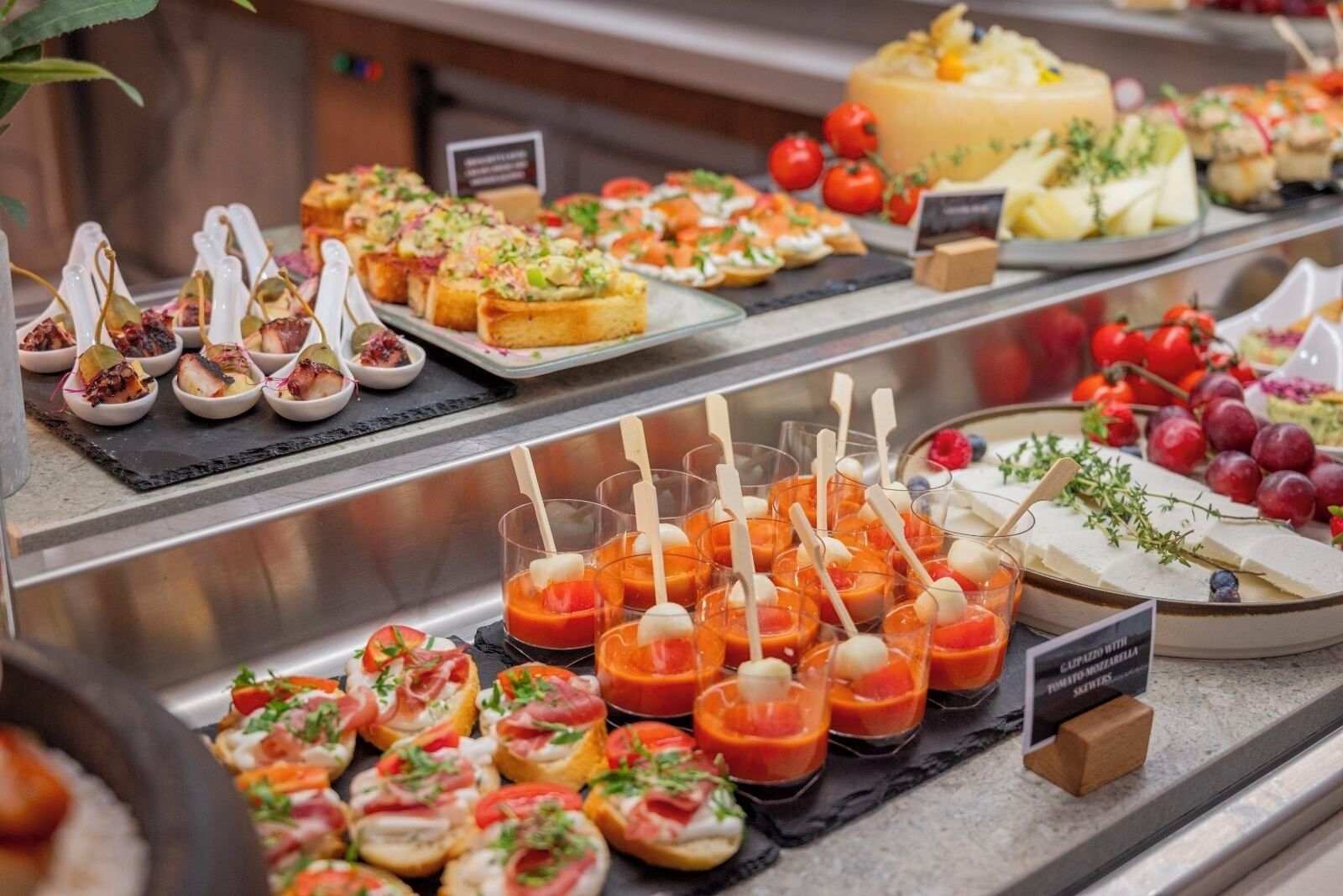 A buffet with various food items including appetizers, cheeses, and fruits.