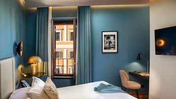 A hotel room with a bed, a desk, a chair, a lamp, and a framed picture on the wall.