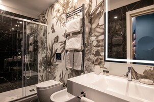 A modern bathroom with a glass-enclosed shower, a white sink, and a large mirror.