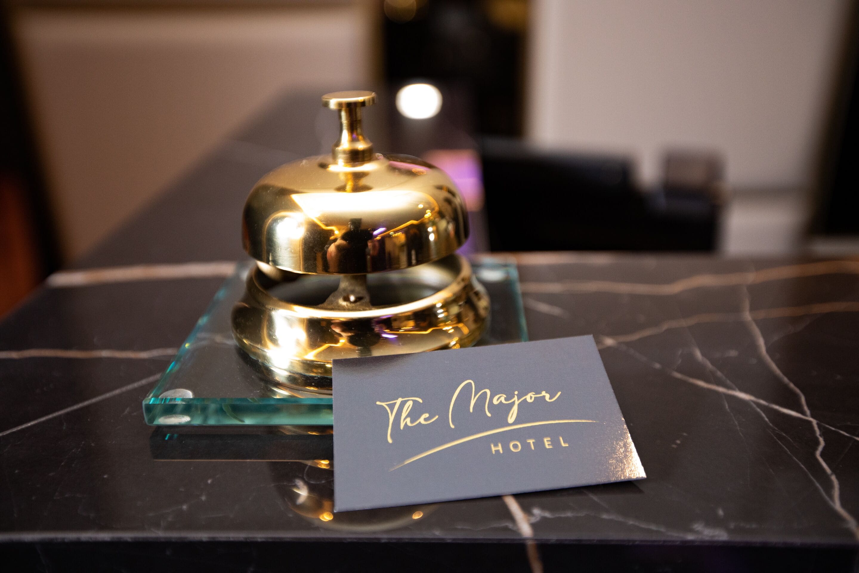 Una habitación de hotel con una mesa de mármol, una campana dorada y un letrero que dice "The Major Hotel".