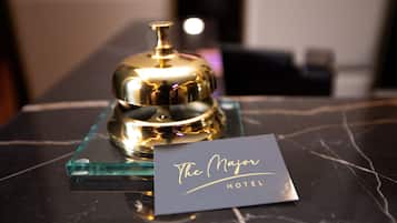Una habitación de hotel con una mesa de mármol, una campana dorada y un letrero que dice "The Major Hotel".