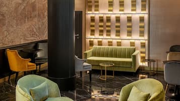 A modern lobby with a large cylindrical column, a green sofa, and two armchairs.
