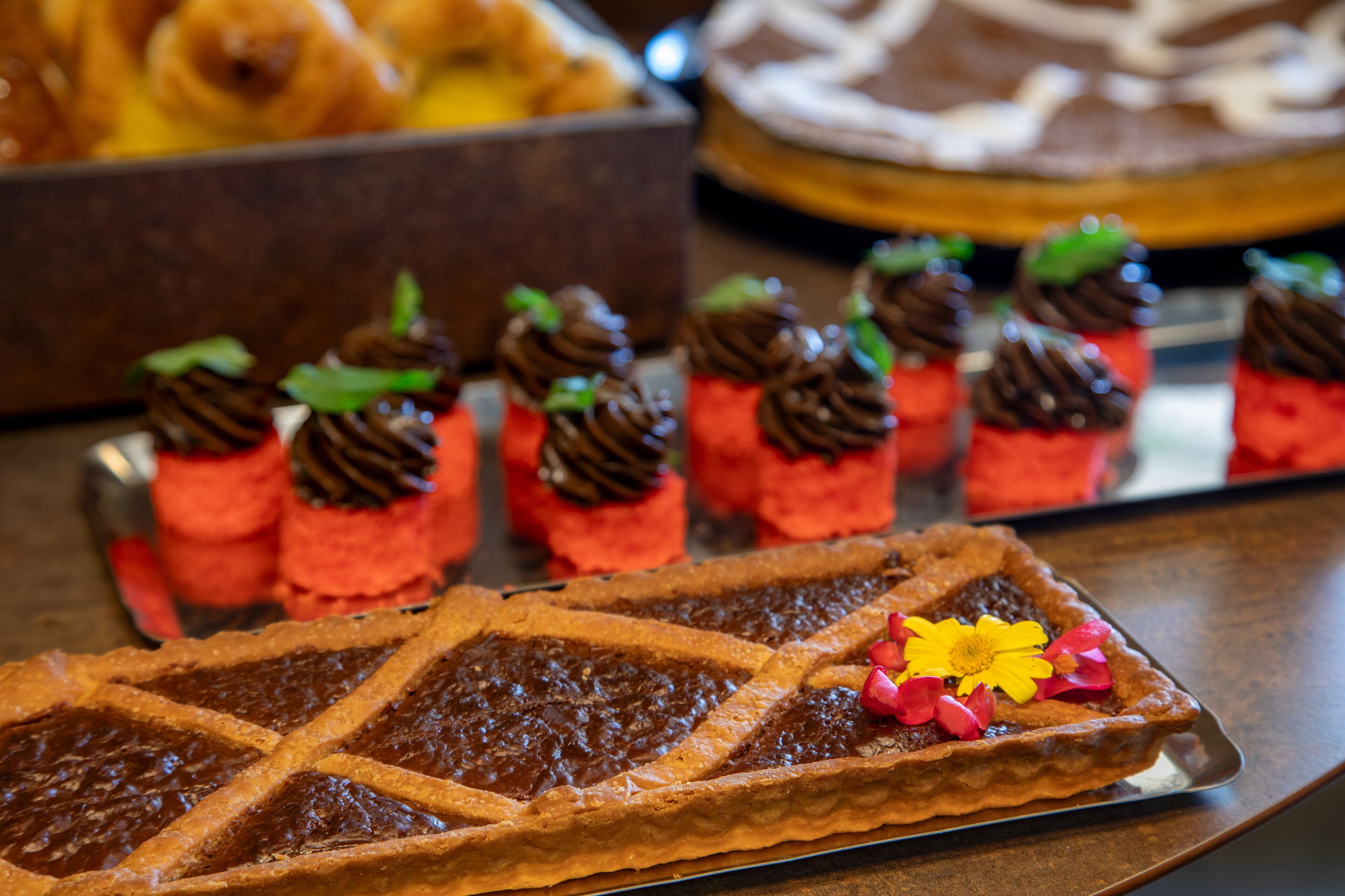 Una bandeja de postres con tartaletas y una tarta de chocolate.