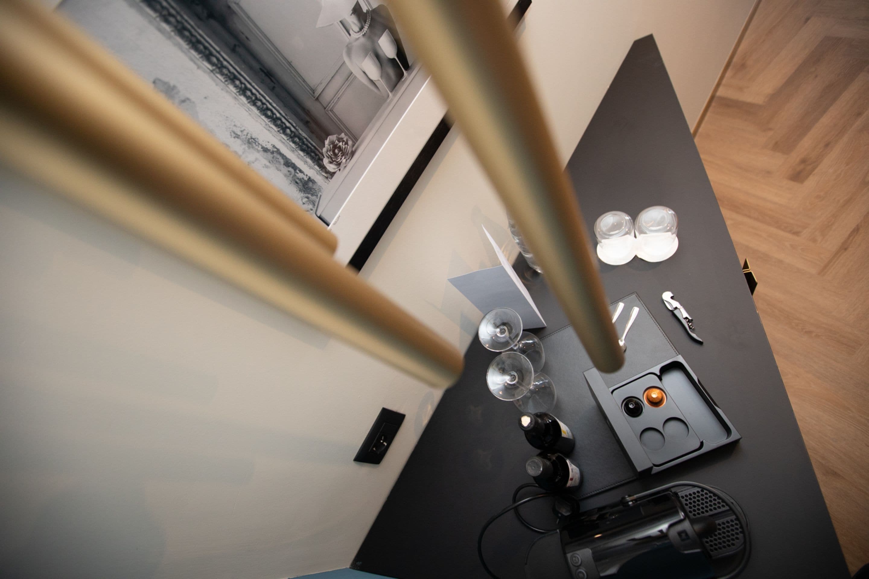 A modern kitchen with a black countertop, wine glasses, a knife block, and a coffee machine.