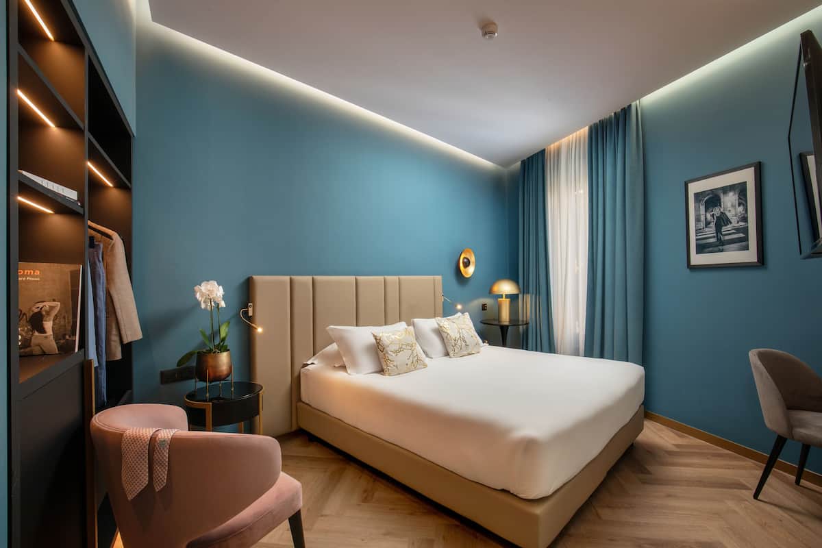 Une chambre à coucher moderne avec un grand lit, une table de chevet avec une lampe, une chaise et une armoire.