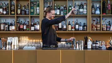 Un bar con scaffali pieni di bottiglie di liquore e un barista che prepara un cocktail.