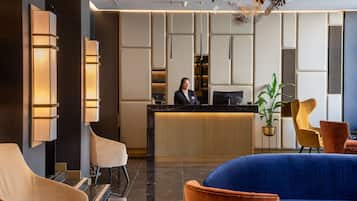 A modern reception area with a marble floor, a reception desk, and a seating area with plush chairs.