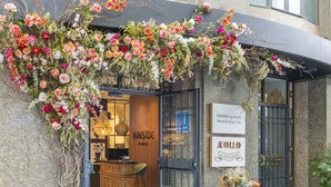 Eingang eines Boutique-Hotels mit Holztresen, einem Fahrrad mit Korb und Schildern für 'INNSIDE by Melia' und 'AOLLO LE-TAVERNIER'.