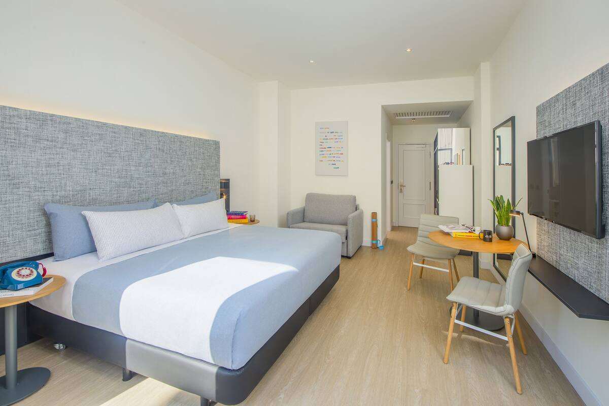 Una camera d'albergo moderna con un letto grande, una scrivania, un tavolo da pranzo e una televisione.