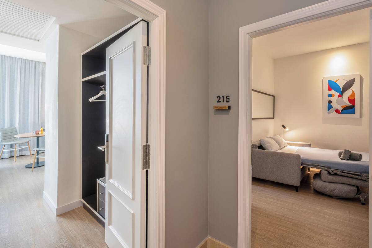 Ein Hotelzimmer mit Bett, Sofa, Schreibtisch und Kleiderschrank.