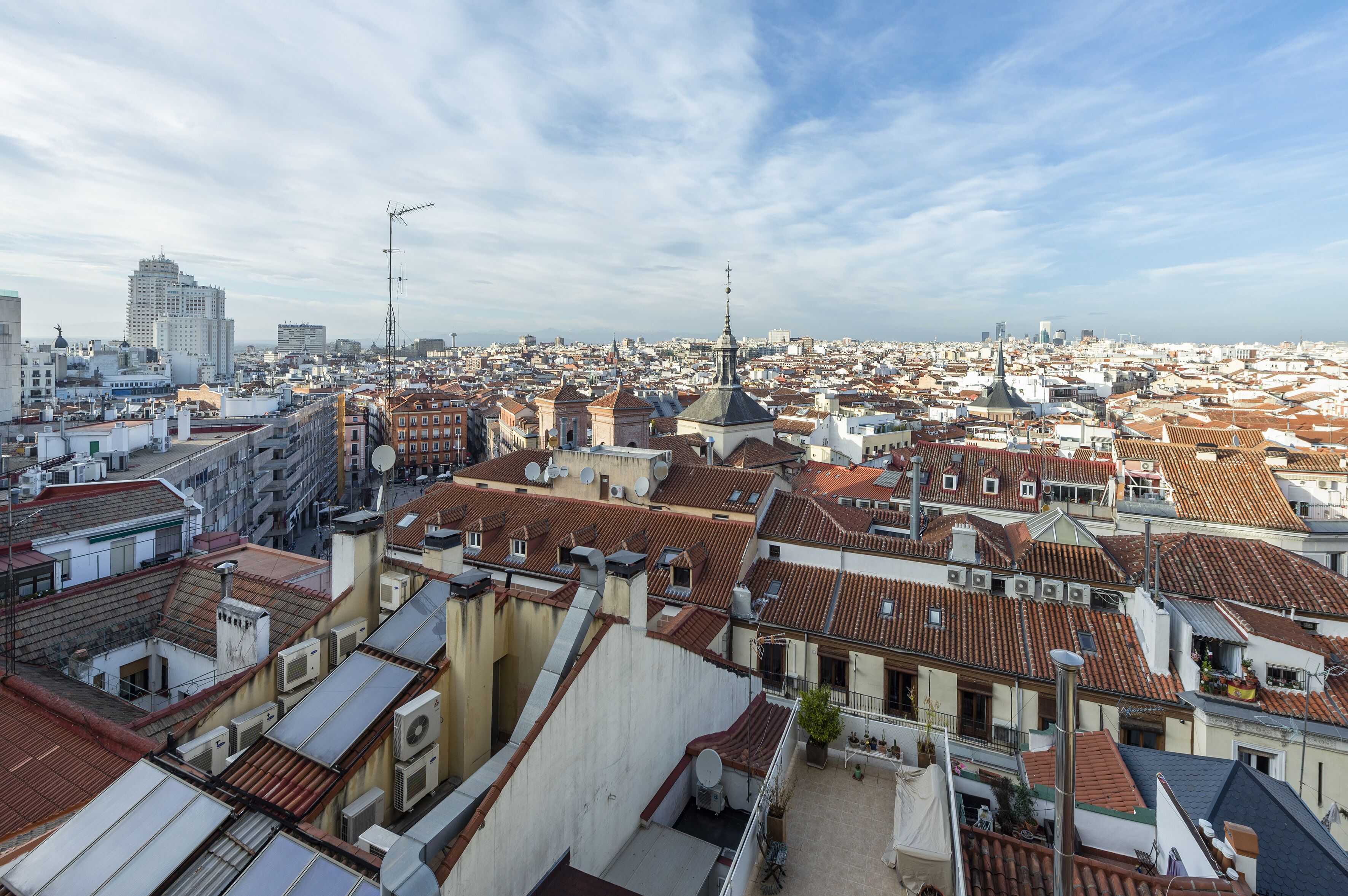 Un paisaje urbano con edificios muy juntos, algunos con antenas y parabólicas visibles, y un cielo despejado.