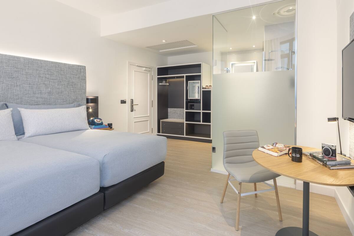 Una camera d'albergo moderna con un letto grande, una scrivania con una sedia, un armadio e uno specchio.