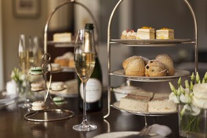 A tiered dessert stand with various pastries and a glass of champagne.