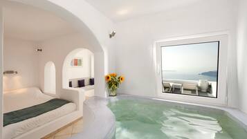 Quarto moderno com uma grande janela, banheira de hidromassagem e vista para o mar.