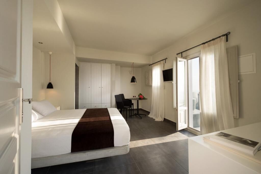 A hotel room with a bed, a desk, a chair, a television, and a bathroom.