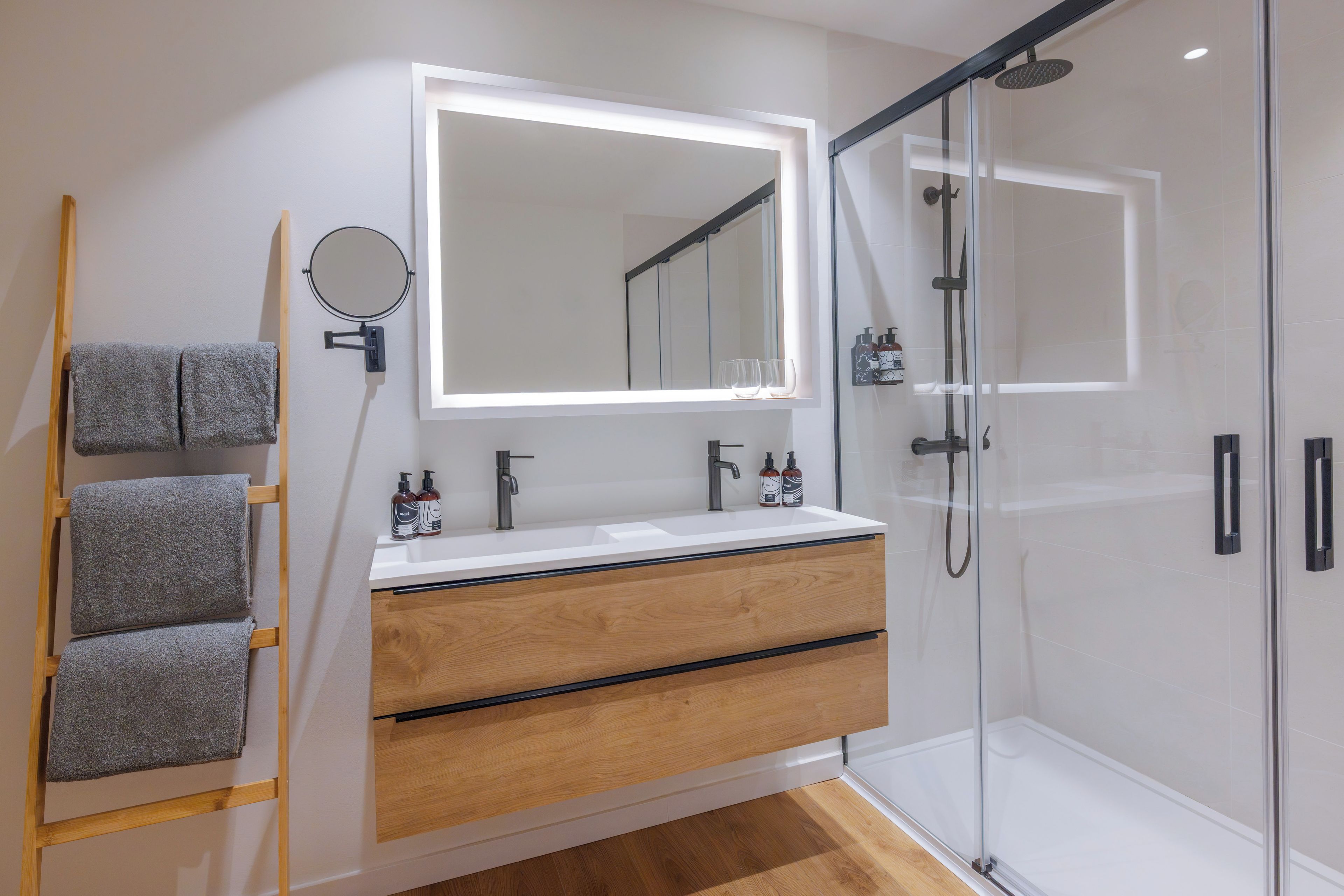 A modern bathroom with a vanity, a mirror, a towel rack, and a shower.