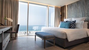 A hotel room with a large bed, a desk, and a view of the ocean.