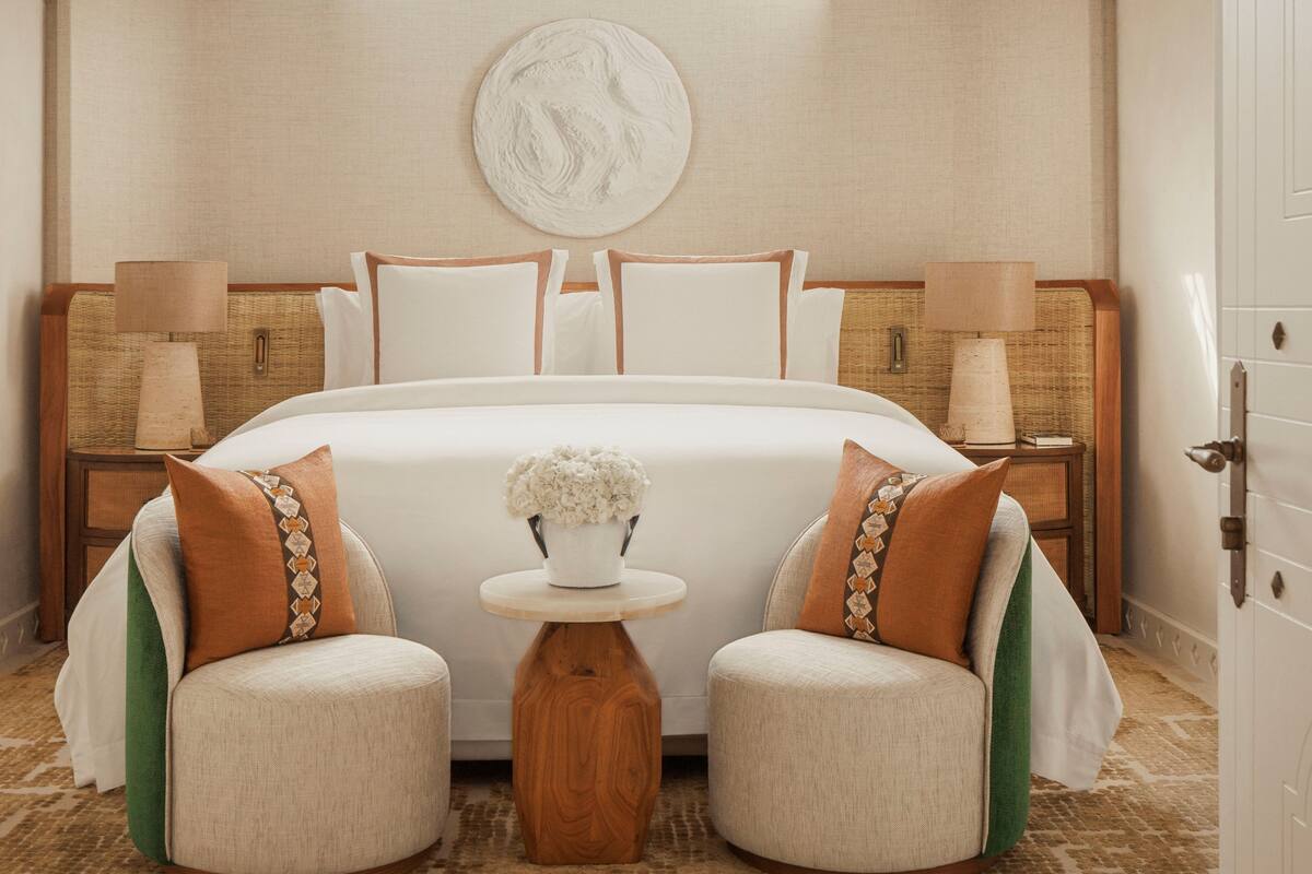 Una habitación de hotel con una cama grande, dos mesitas de noche, una pequeña mesa redonda y un adorno en la pared.
