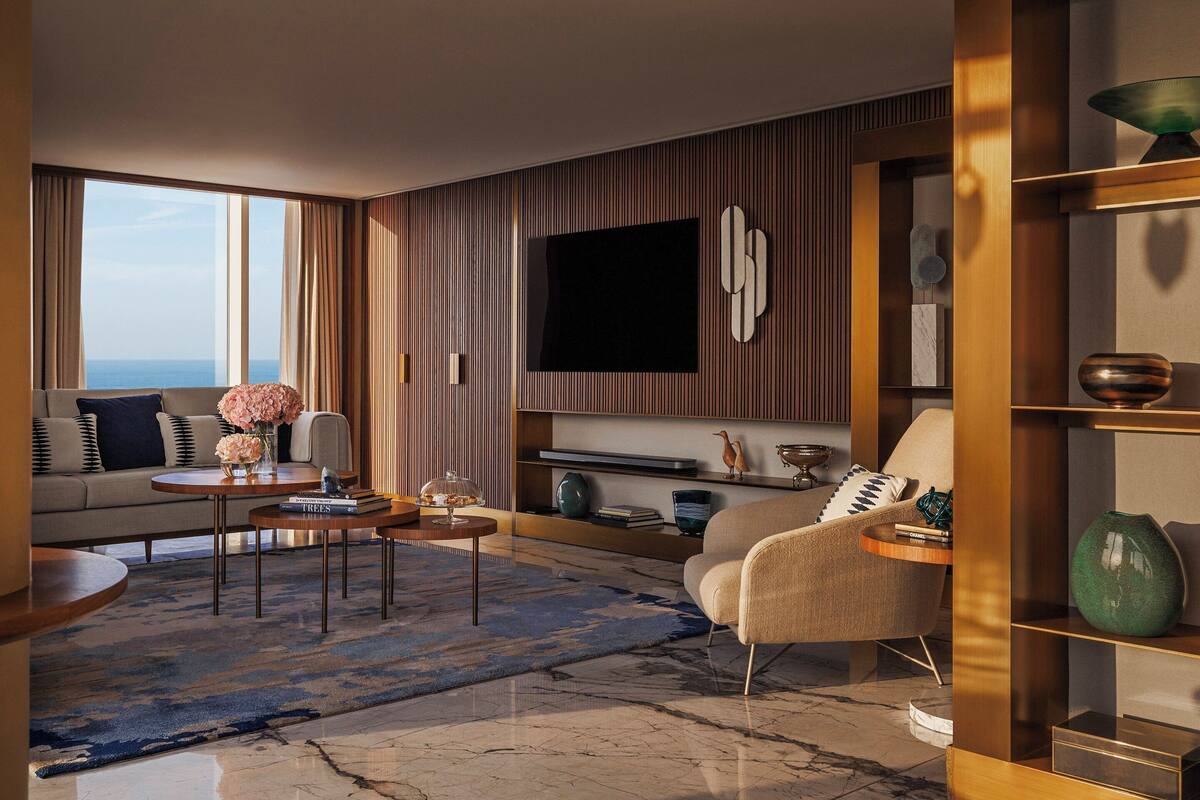 Una sala de estar moderna con un sofá, sillones, una mesa de centro y un televisor montado en la pared.
