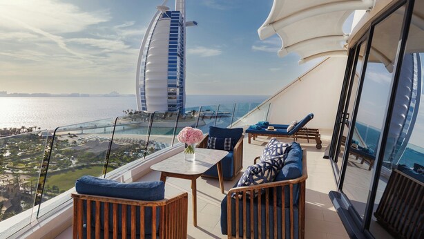 En balkon med udsigt til Burj Al Arab, møbleret med sofaer og et bord.