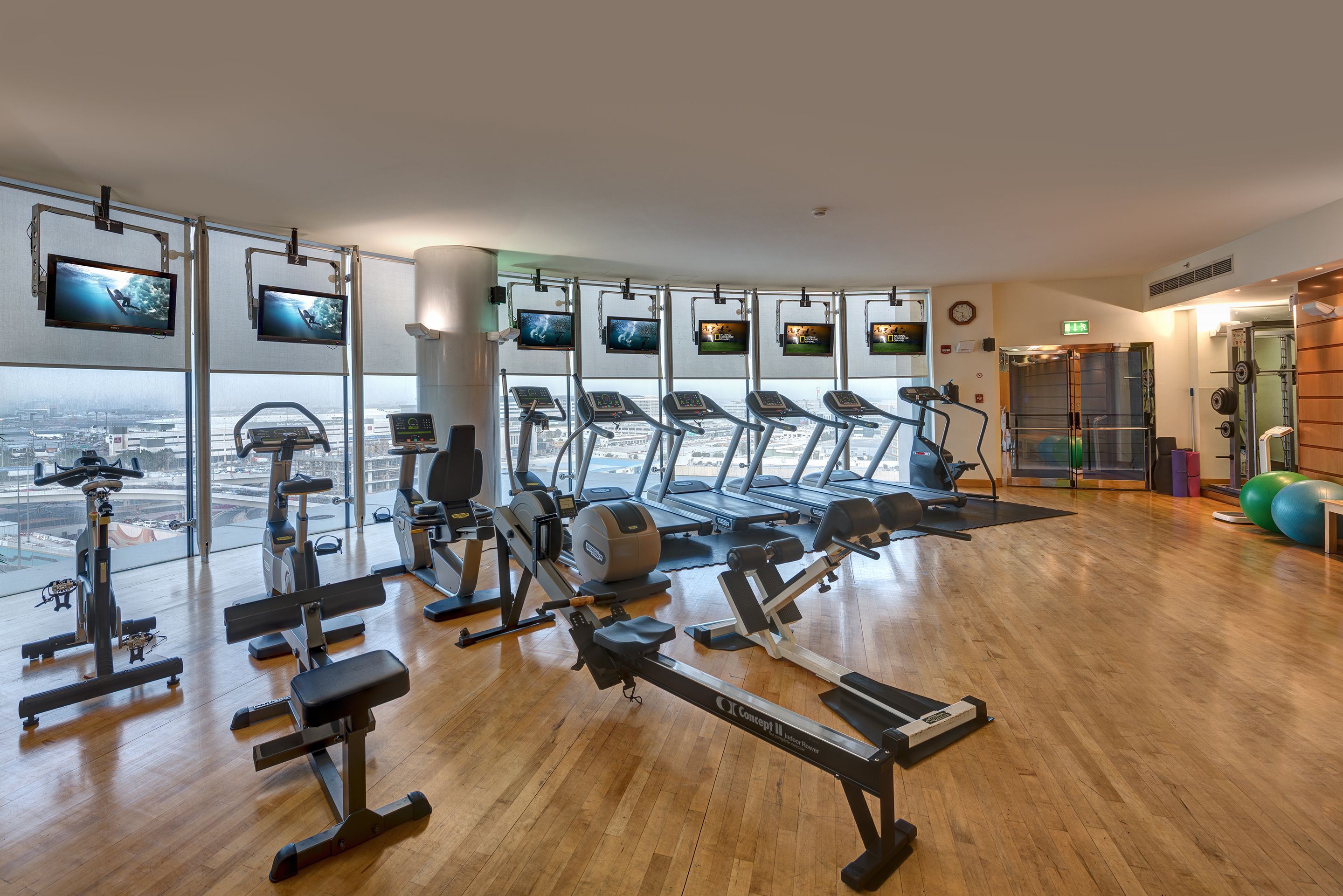 A gym with various exercise equipment, large windows, and a view of the city.