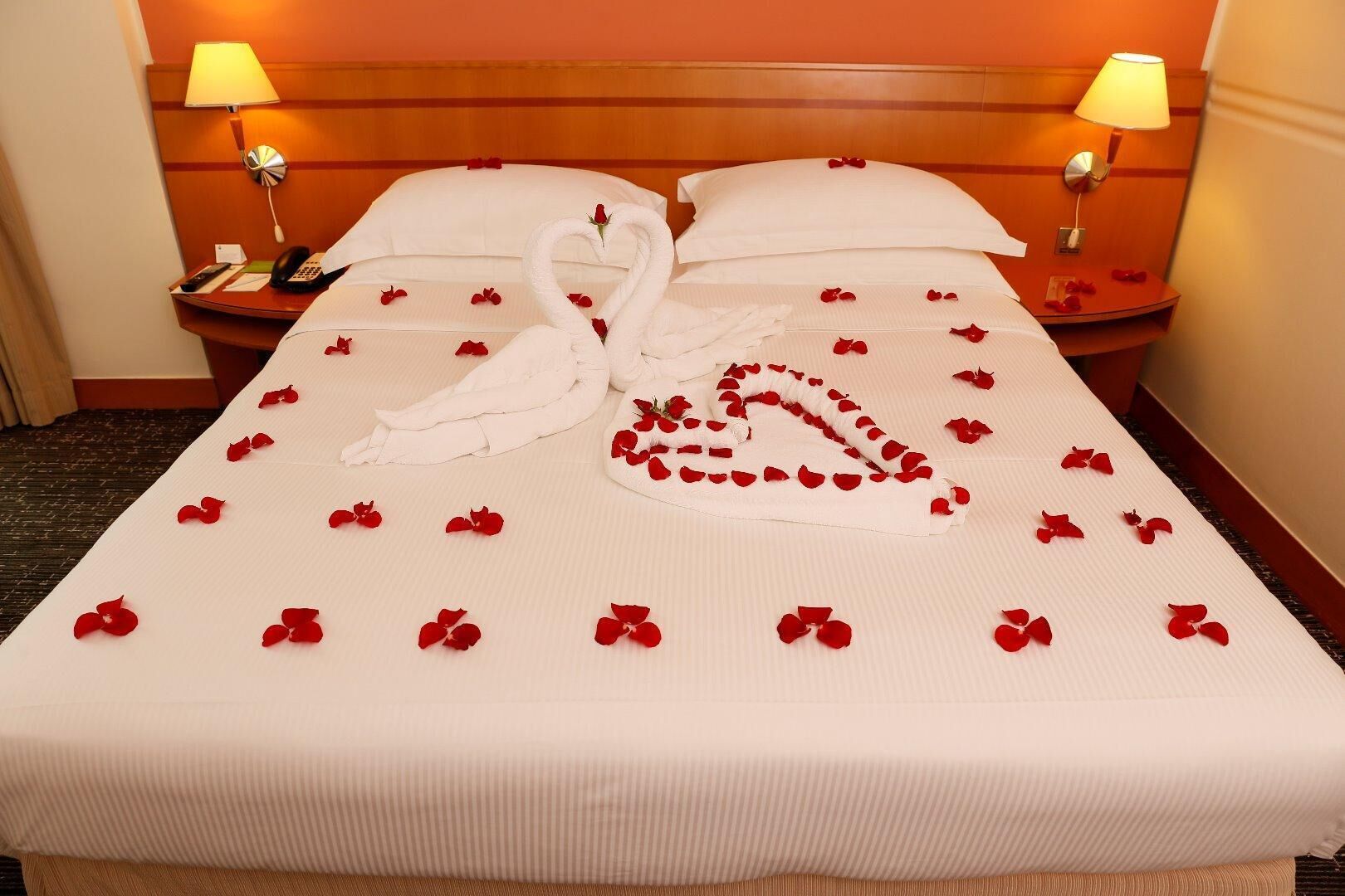 Habitació d'hotel amb un llit ben fet, dues làmpades de nit i un telèfon a la tauleta de nit.