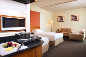 Une chambre d’hôtel avec une kitchenette, deux lits, un canapé et une table à manger.