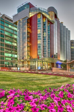 A modern hotel with a glass facade, multiple floors, and a prominent entrance with flags. - J5 Hotels - Port Saeed (Dubai)