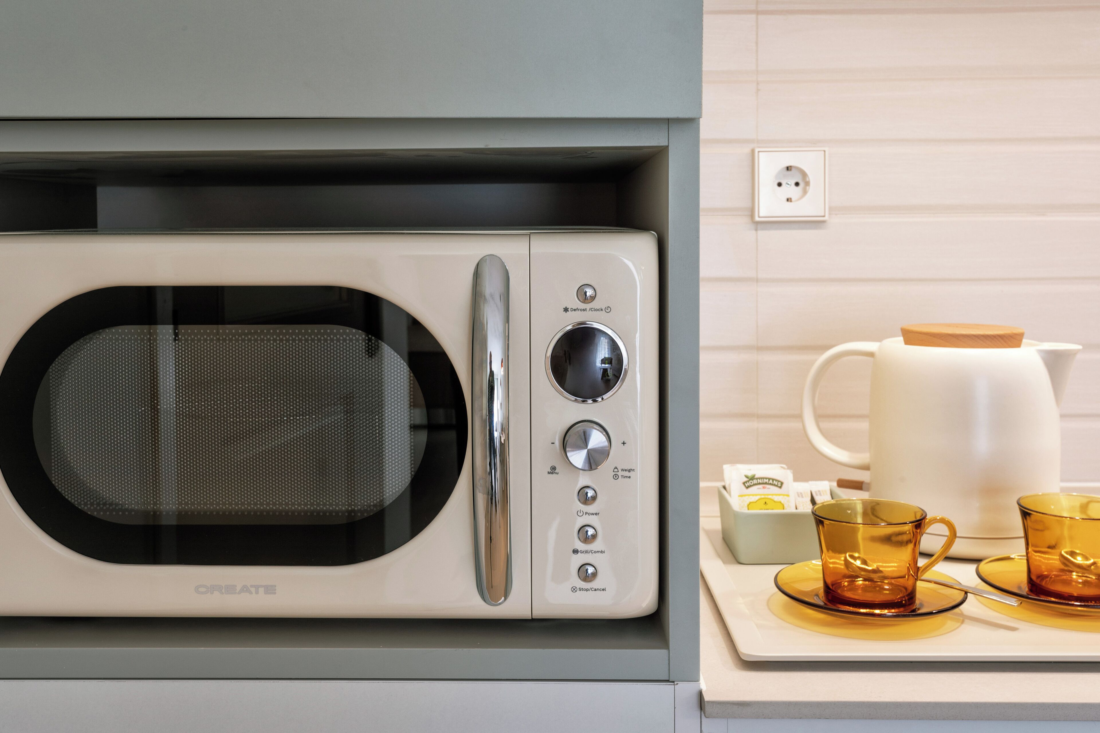 A kitchen with a microwave, a coffee maker, and a tray with two cups.