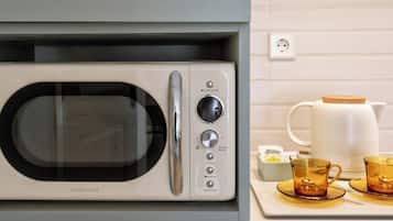 A kitchen with a microwave, a coffee maker, and a tray with two cups.