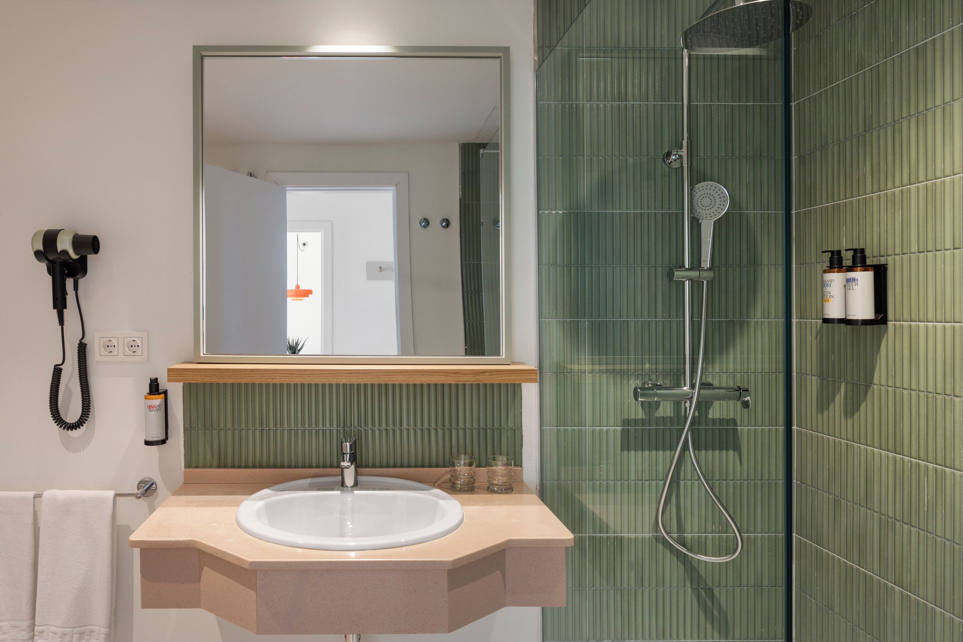 A bathroom with a sink, mirror, and shower.