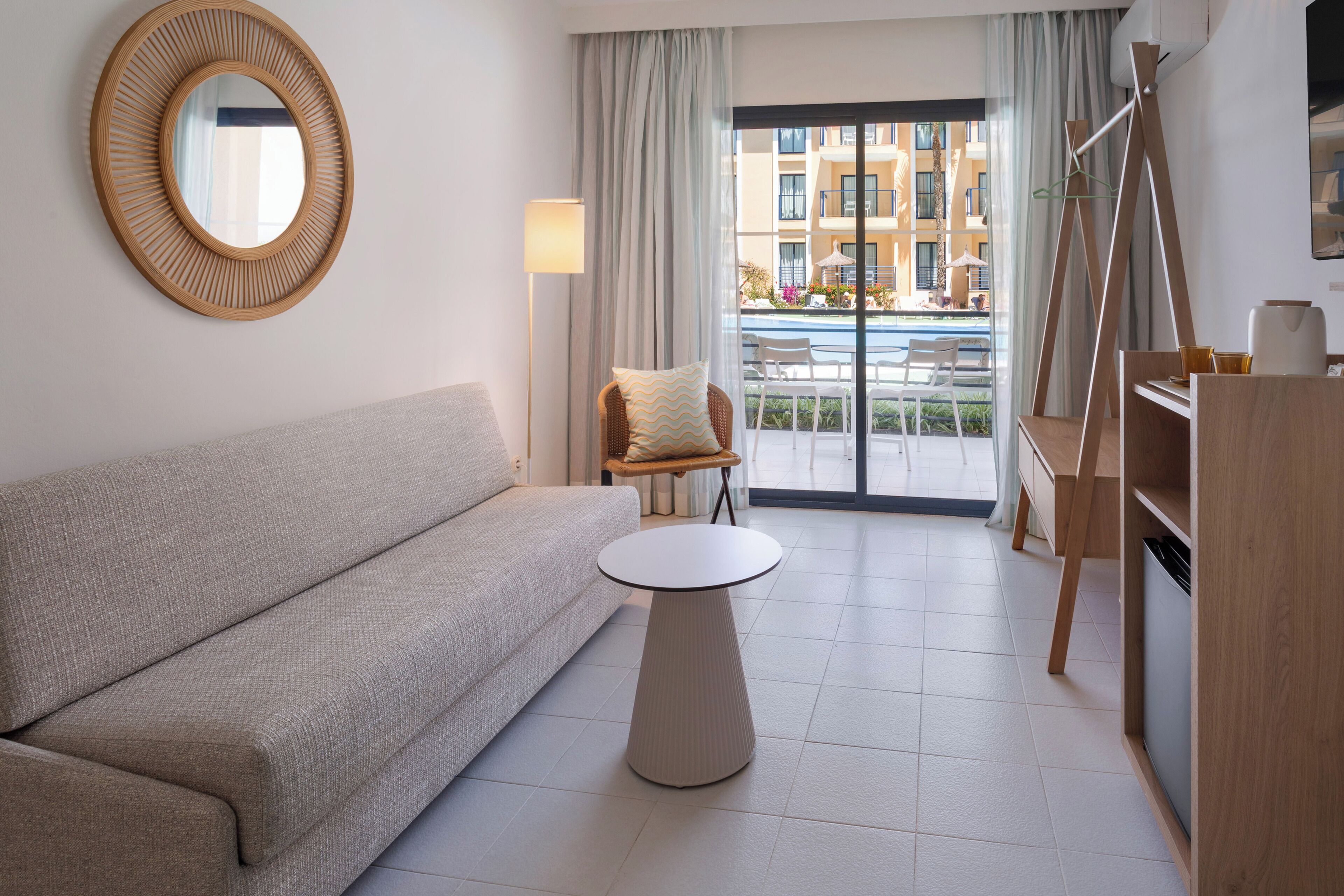 A modern living room with a sofa, a round table, a chair, and a view of the outdoor balcony.