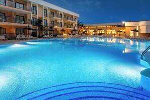 Una piscina al aire libre, sombrillas, sillones reclinables de piscina