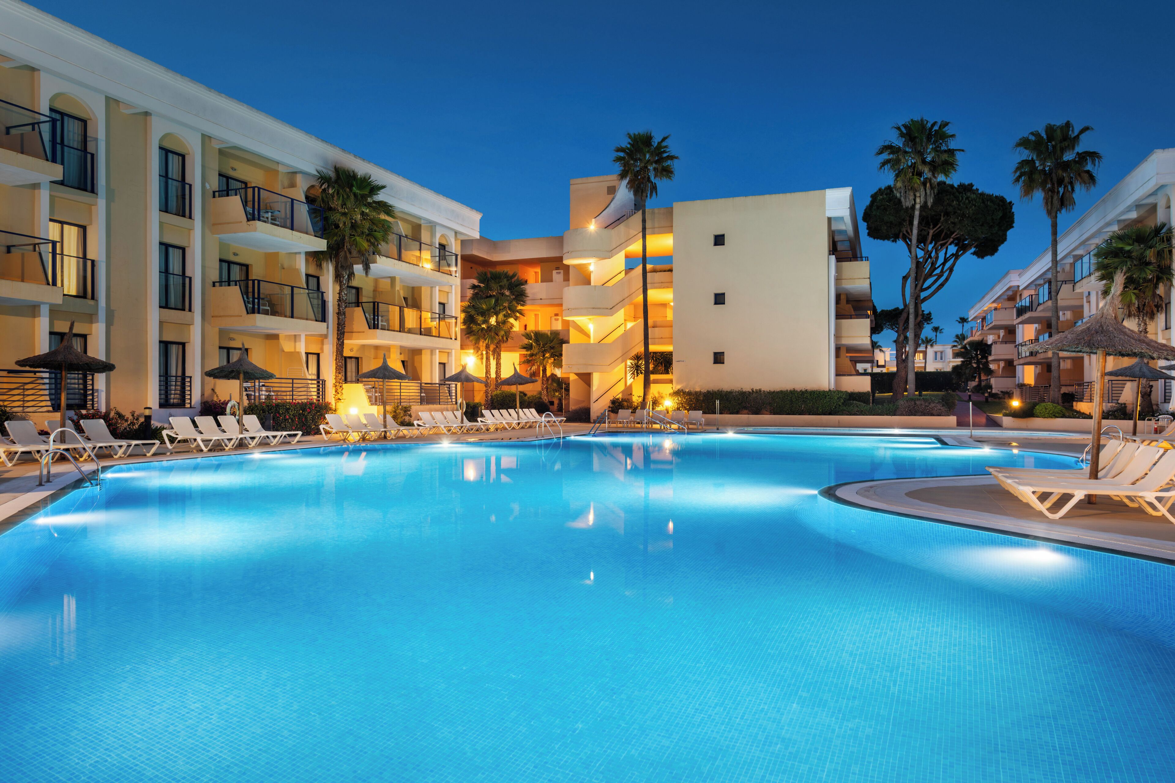Una piscina al aire libre, sombrillas, tumbonas