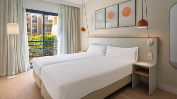 Une chambre d’hôtel avec un grand lit, une table de chevet, une lampe et une vue sur le balcon extérieur.