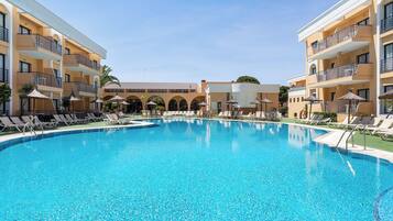 Alberca al aire libre, sombrillas en la alberca y camastros