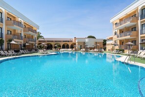 Een buitenzwembad, parasols bij het zwembad en ligstoelen