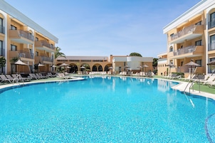 Una piscina al aire libre, sombrillas, sillones reclinables de piscina