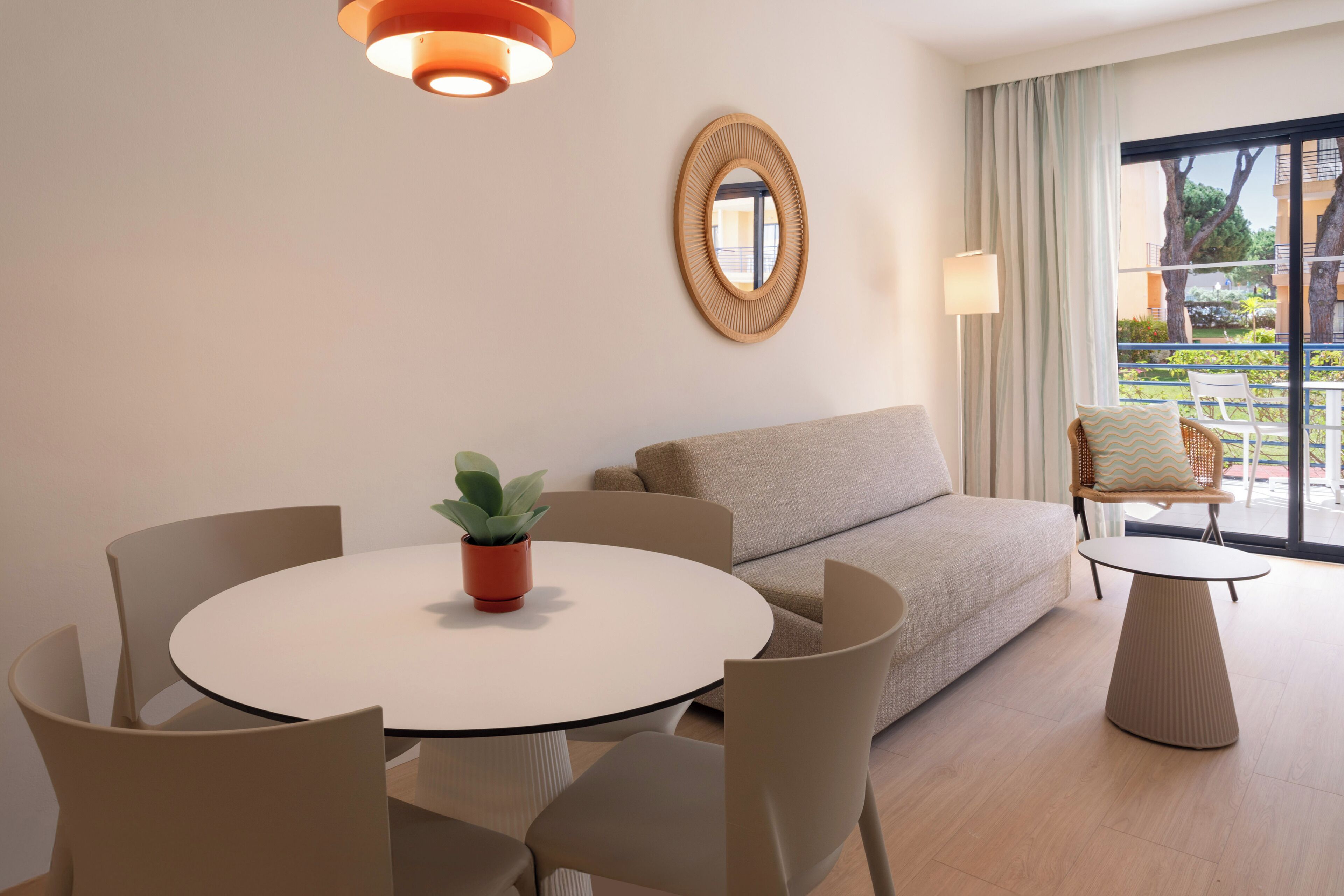 Una sala moderna con una mesa redonda, un sofá color beige y una planta en maceta.